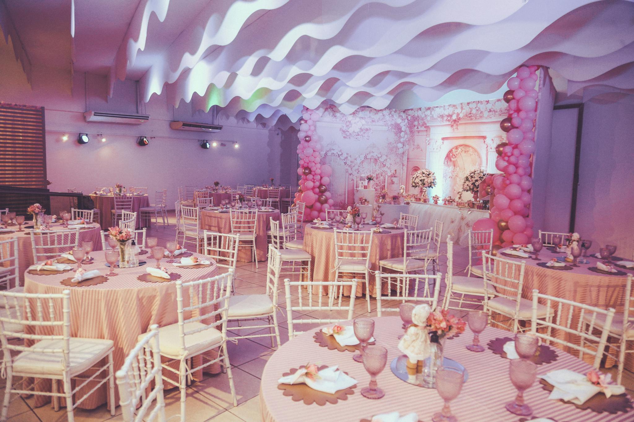 Beautiful pink-themed event setup with balloons and decorated tables.